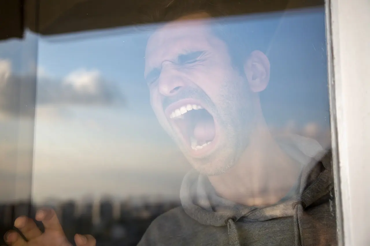 man with Histrionic Personality Disorder screaming against a glass window